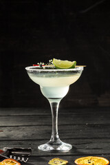 Margarita cocktail in glass with lime slice on the table on black background