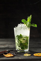 Mojito cocktail with lime and mint in tall glass on the table on black background