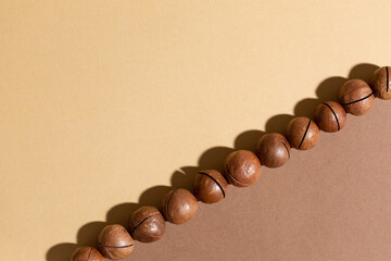Macadamia nuts on beige and brown background. Food background. Top view, flat lay, copy space.