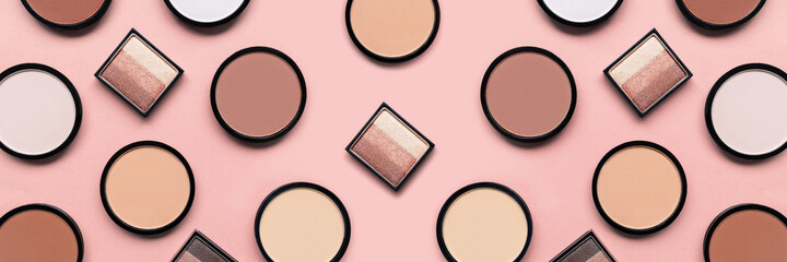 Cosmetic products on pastel pink background. Beige eyeshadow, blush and mineral compact face powder...
