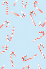 Christmas composition. Red and white candies on blue background. Christmas, winter, new year concept. Minimal style. Flat lay, top view, copy space.
