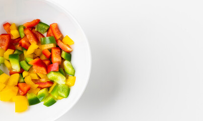 Raw mixed red yellow and green bell pepper cut into small pieces put on a bowl. Healthy vegetables and food on isolated white background and blank space.