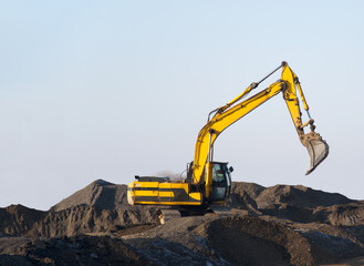 Obraz premium Excavator working on earthmoving at open pit mining. Backhoe digs gravel in quarry. Construction equipment and machinery for quarrying. Recycling of gravel and concrete construction waste