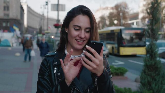 Portrait of young beautiful woman using app on smartphone, smiling and typing texting chatting online, serfing news on mobile phone urban background 4k