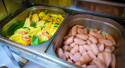 Cooked Frankfurter sausage in metal utensils in a buffet restaurant