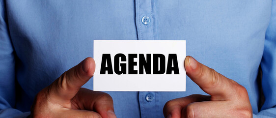 AGENDA is written on a white business card in a man's hands. Business concept
