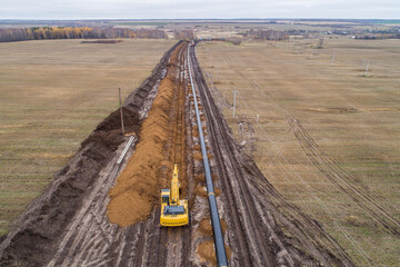 laying the pipeline with an excavator. Autumn, shooting from a drone. Earthworks, infrastructure construction © Александр Ивасенко