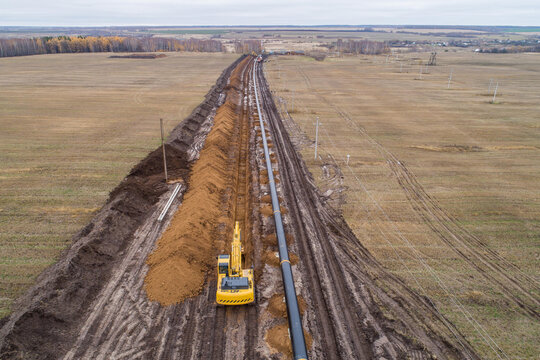 laying the pipeline with an excavator. Autumn, shooting from a drone. Earthworks, infrastructure construction
