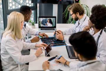 Team of multiracial experienced doctors or scientists, having video conference with their young confident African female expert and talking about the results of patient's CT during clinical trial