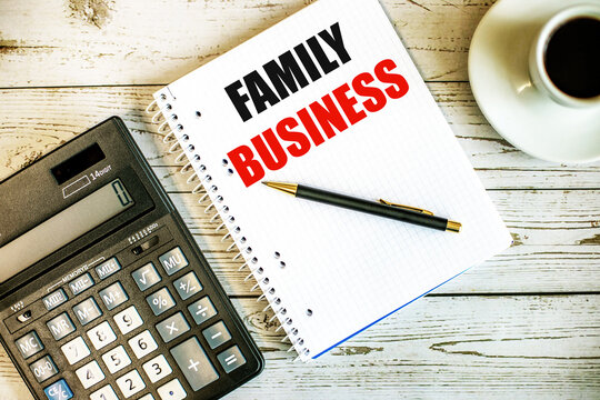 FAMILY BUSINESS written on white paper near coffee and calculator on a light wooden table. Business concept