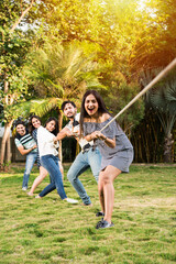Indian asian young friends playing tug of war or rassi khech outdoors
