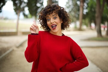 Fototapeta na wymiar Young arab woman wearing casual red sweater in the street, holding finger up having idea and posing