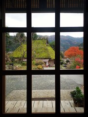 view from the window to the traditional thatched roof in japanese houses at kayabuki no sato with autumn foliage.