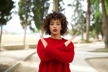 Young beautiful Arab woman standing outdoors wearing red sweater Rejection expression crossing arms doing negative sign, angry face