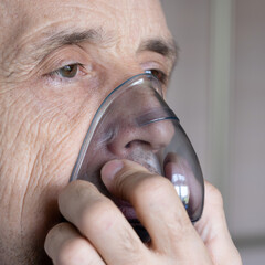 Medical oxygen mask on a man. A man breathes oxygen using a mask. Close-up of an old man doing...