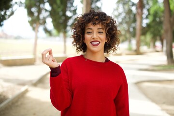 Young beautiful Arab woman standing outdoors wearing red sweater pointing up with hand showing up seven fingers gesture in Chinese sign language QĪ.