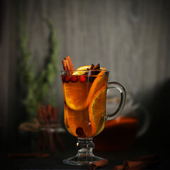 mulled wine tea with cinnamon and orange stands on a dark background	