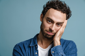 Tired unshaven handsome guy posing and looking at camera