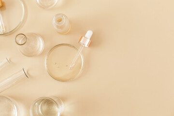 Laboratory glassware and pipette with serum and oil on beige background. Natural medicine, cosmetic research, bio science, organic skin care products. Concept skincare. Dermatology.Flat lay, top view.