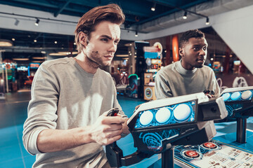 Man with cool hairstyle stands behind a joystick.