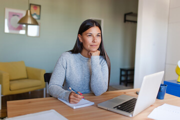 Pensive woman thinking what to write at home.