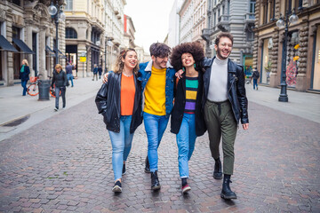 Group of friends tourist walking together hugging outdoors in the city downtown sightseeing having fun, smiling and enjoying vacation