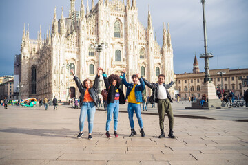 Fototapeta premium Group of for multiethnic people friends celebrating in front of milan cathedral rising their arms victorious thrilled after big win