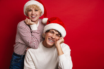 Beautiful happy couple in Santa Claus hats smiling at camera