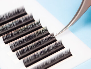 Tweezers remove lashes from the artificial lash tape. The work of a lashmaker.