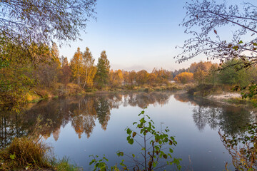 view of a calm river, autumn, Sunny day. In the foreground are beautiful twigs and leaves. Reflection