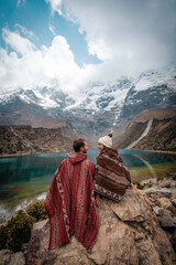 A young couple on vacation sitting on the rocks at Laguna Humantay, Peru