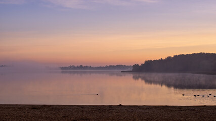 Horizontal landscape of a beach and a lake in sunrise.