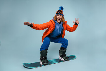 Handsome excited sportsman riding on a snowboard