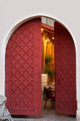 old iron red doors leading to a cozy warm courtyard, cafe. Europe.