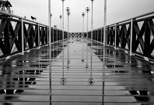 Black and white photography of a wet pier with lanterns in a day.