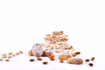 Traditional spanish sweets surrounded by peeled and unpeeled almonds with almond nougat chunks at the back. Traditional sweets and Christmas concept.