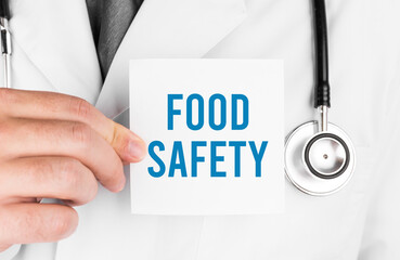Doctor holding a card with text FOOD SAFETY, medical concept