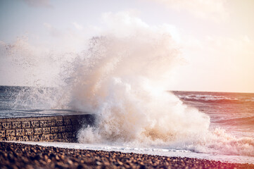 Massive waves splashing against stone groin on seafront in stormy weather