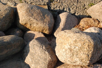 Stones on the shore against the wall.
Large stones lie close to each other against the wall on the shore of the Gulf of Finland. The setting sun illuminates the stones. The stones cast shadows on each