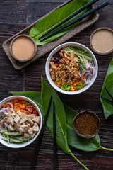Variety of healthy organic poke bowls with tuna, chicken, tofu and cucumber, rice, carrots, onion served on wooden table with tropical leaves. Healthy lifestyle