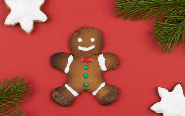 gingerbread men on a red background decorated with spruce branches. traditional Christmas gingerbread cookies. holiday treats handmade. top view, copy space 