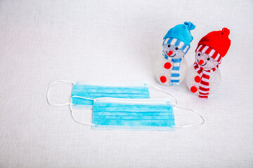 decorative snowmen and a medical mask on a white background, there is a place for text, the concept of meeting the new year against the background of the coronavirus epidemic. Save your life, be quara