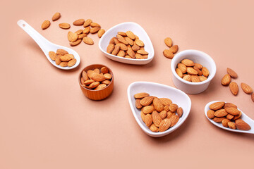 Almonds with spoons and white plates on beige background