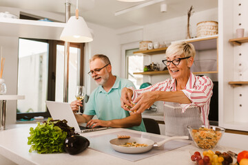 Senior couple preparing food in the kitchen, having fun.