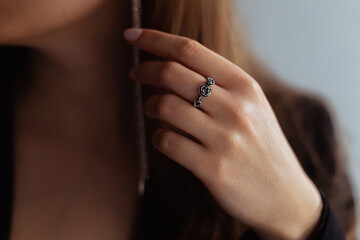 Silver rose ring on a middle finger of a young blonde lady. Close-up.