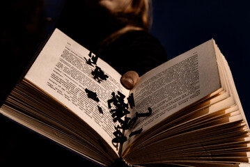 Person holding an open book with letters falling out