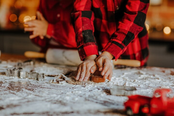 Child's hands making cookies on the table with rolling pin, molds and flour.