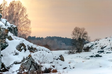 Winter landscape with frozen river, snow, rocks and trees