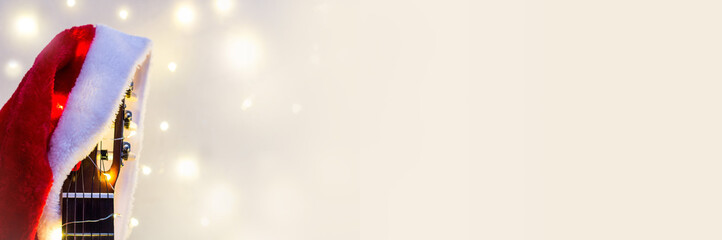 Banner of Acoustic Guitar with red Santa hat and light garland. Christmas music song concept with copyspace