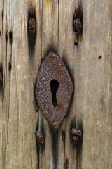 Old rusty key hole in an old wooden door